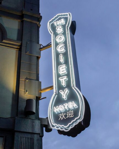 The Society Hotel sign lit up.