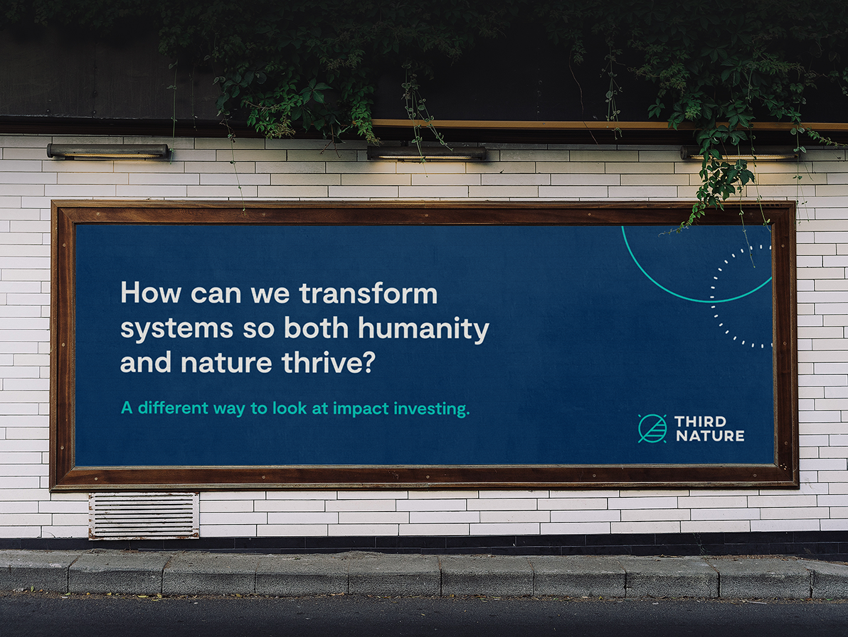 A billboard on a white tiled wall with green vines surrounding that reads "How can we transform systems so both humanity and nature thrive? A different way to look at impact investing. Third Nature."
