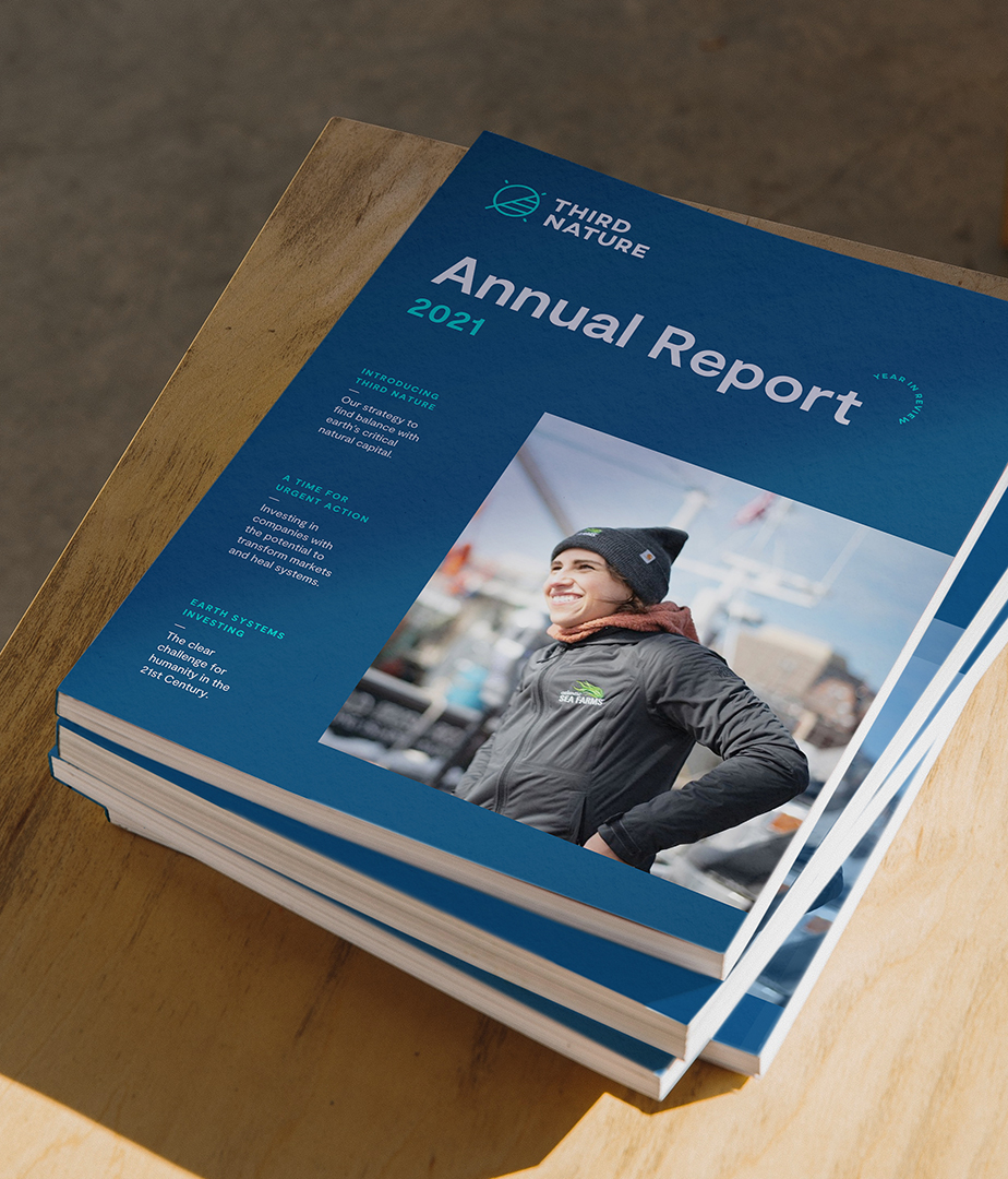 A stack of Third Nature Investments 2021 annual report booklets on a wooden table.