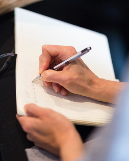 Person jotting down notes in a notebook.