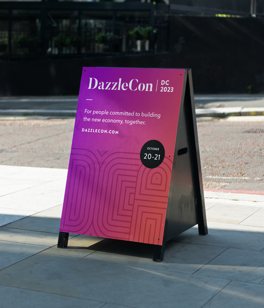 An A-frame sign placed outside the event reading, "DazzleCon '23: For people comitted to building the new economy together."