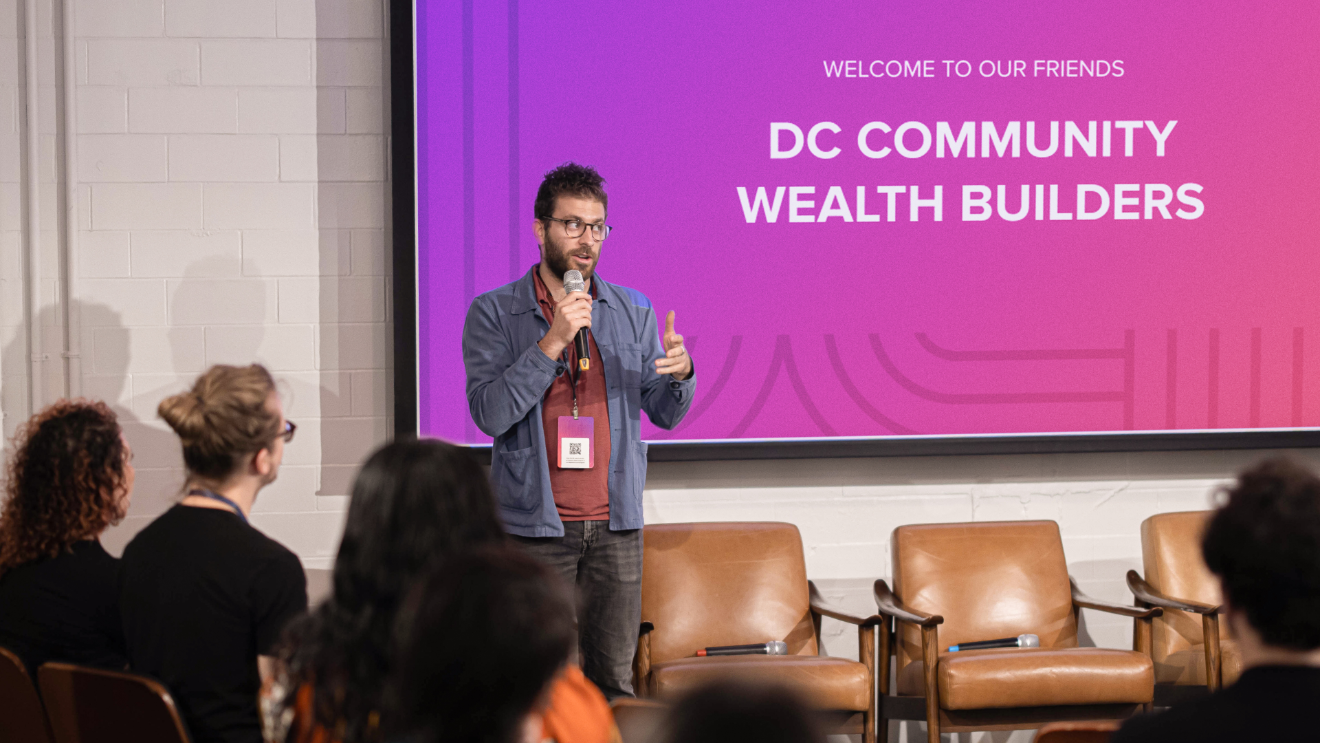An event speaker standing in front of a design presentation slide matching the event branding.
