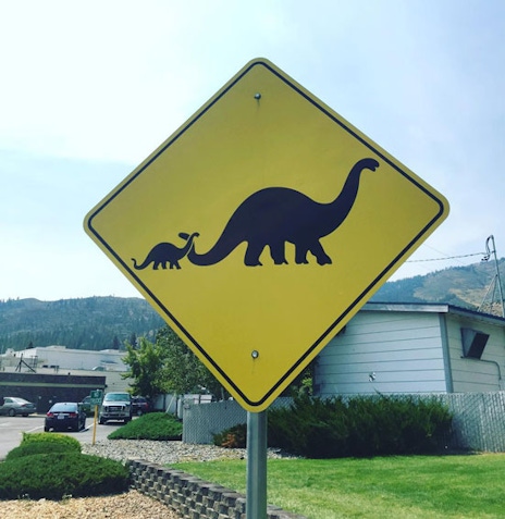 A yield sign with two dinosaur silhouettes inside
