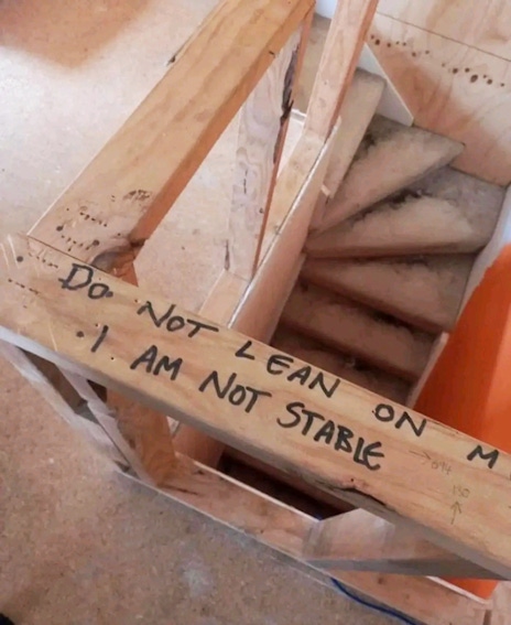 A spiral staircase under construction with the message Do not lean on me, I am not stable.