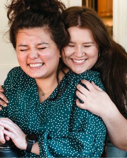 Selena (right) and Madison (left) hugging and smiling at a team retreat