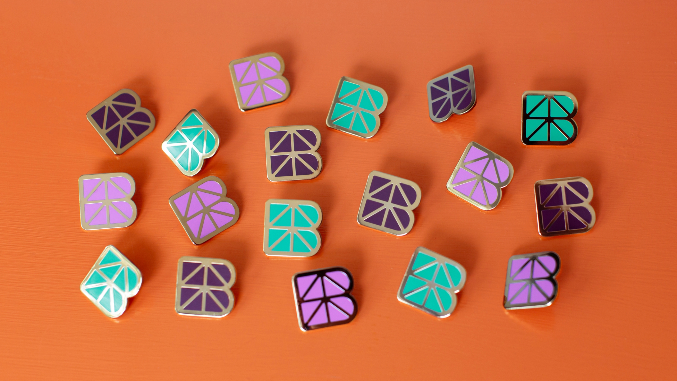 BUF enamel pins laid on an orange background.