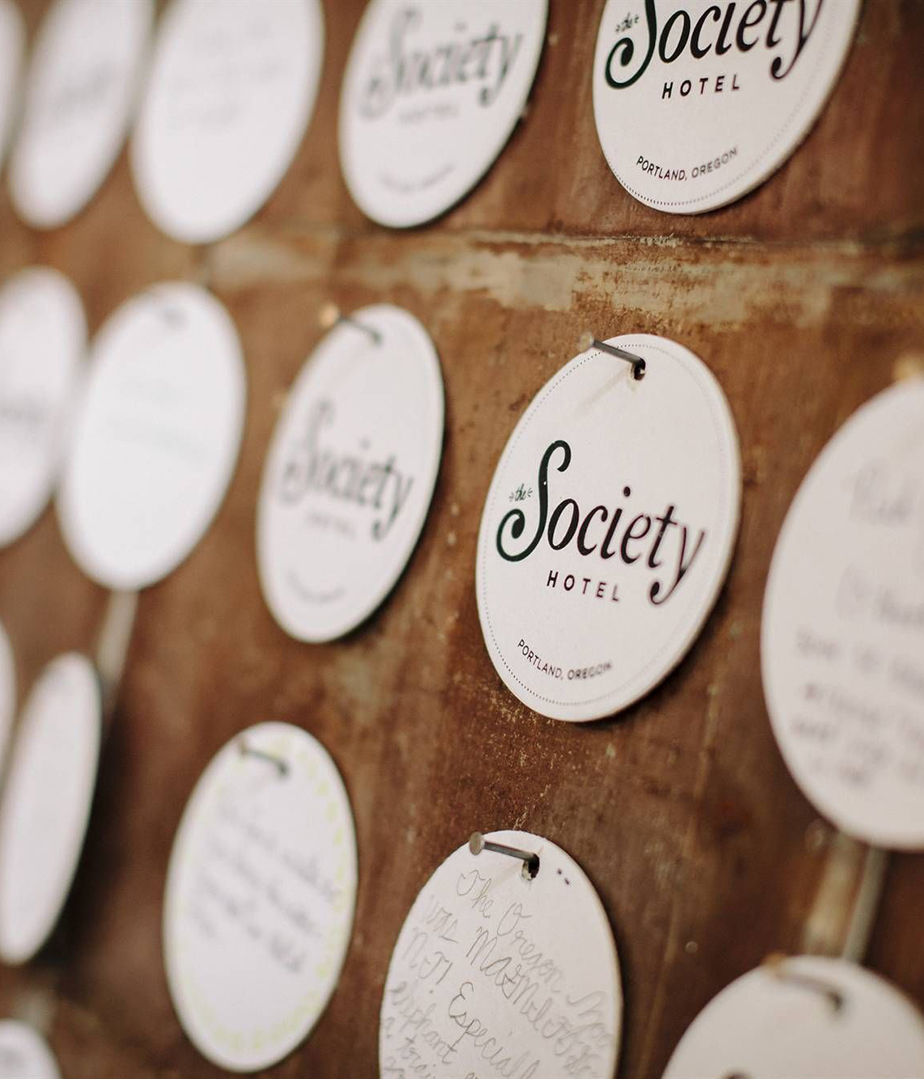 The Society Hotel round placards hanging from nails on a wooden board.