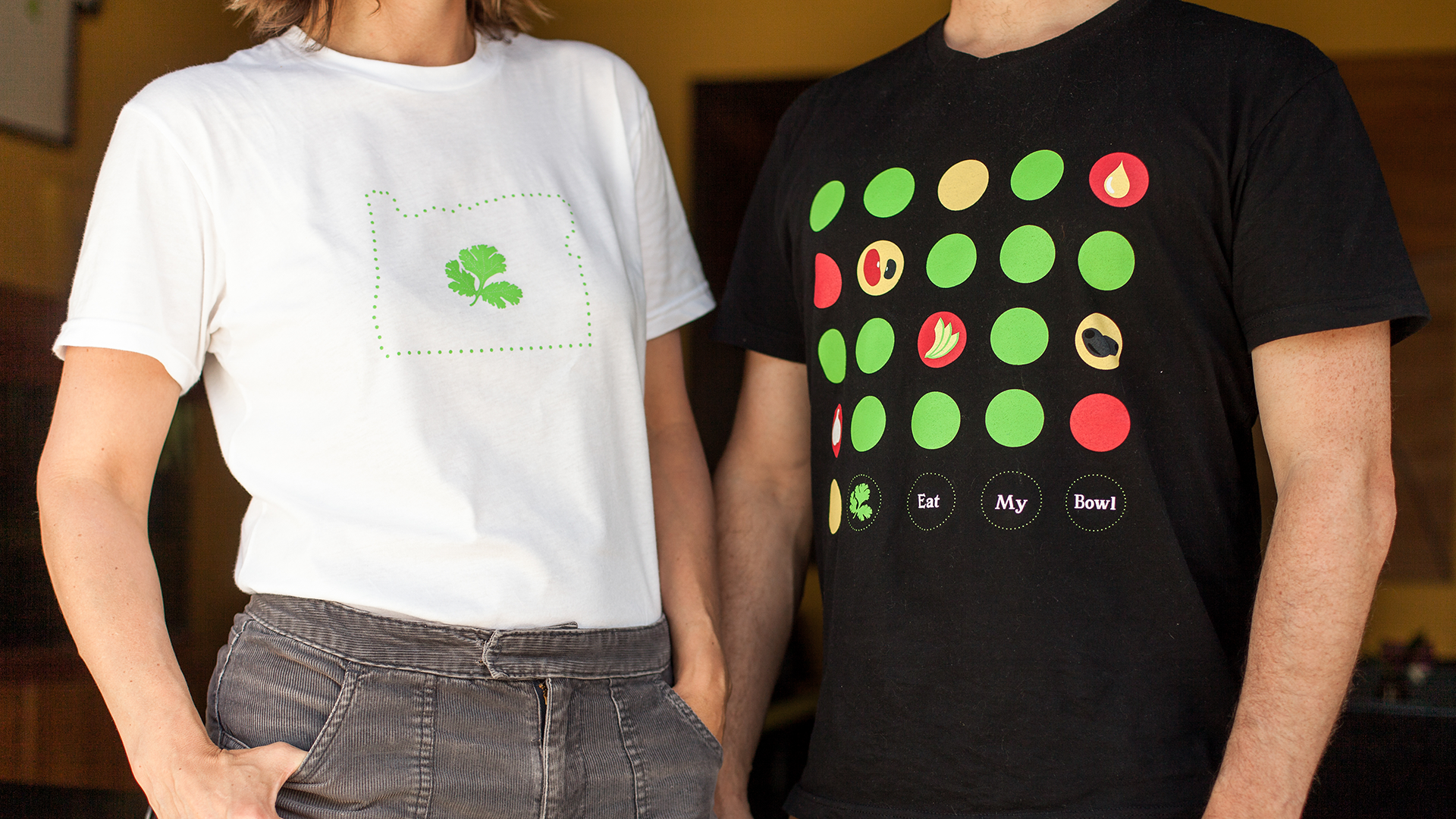 Two of the shirts we designed for Whole Bowl. The first is a white shirt with the Oregon state silhouette with the Whole Bowl cilantro leaf in the center. The second shirt features the illustrated menu items with the words "Eat my bowl" at the bottom.